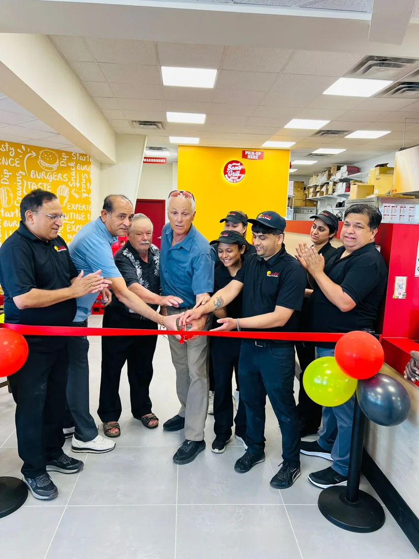 Local representatives and Sam's Grill staff cutting the ribbon at a new store opening